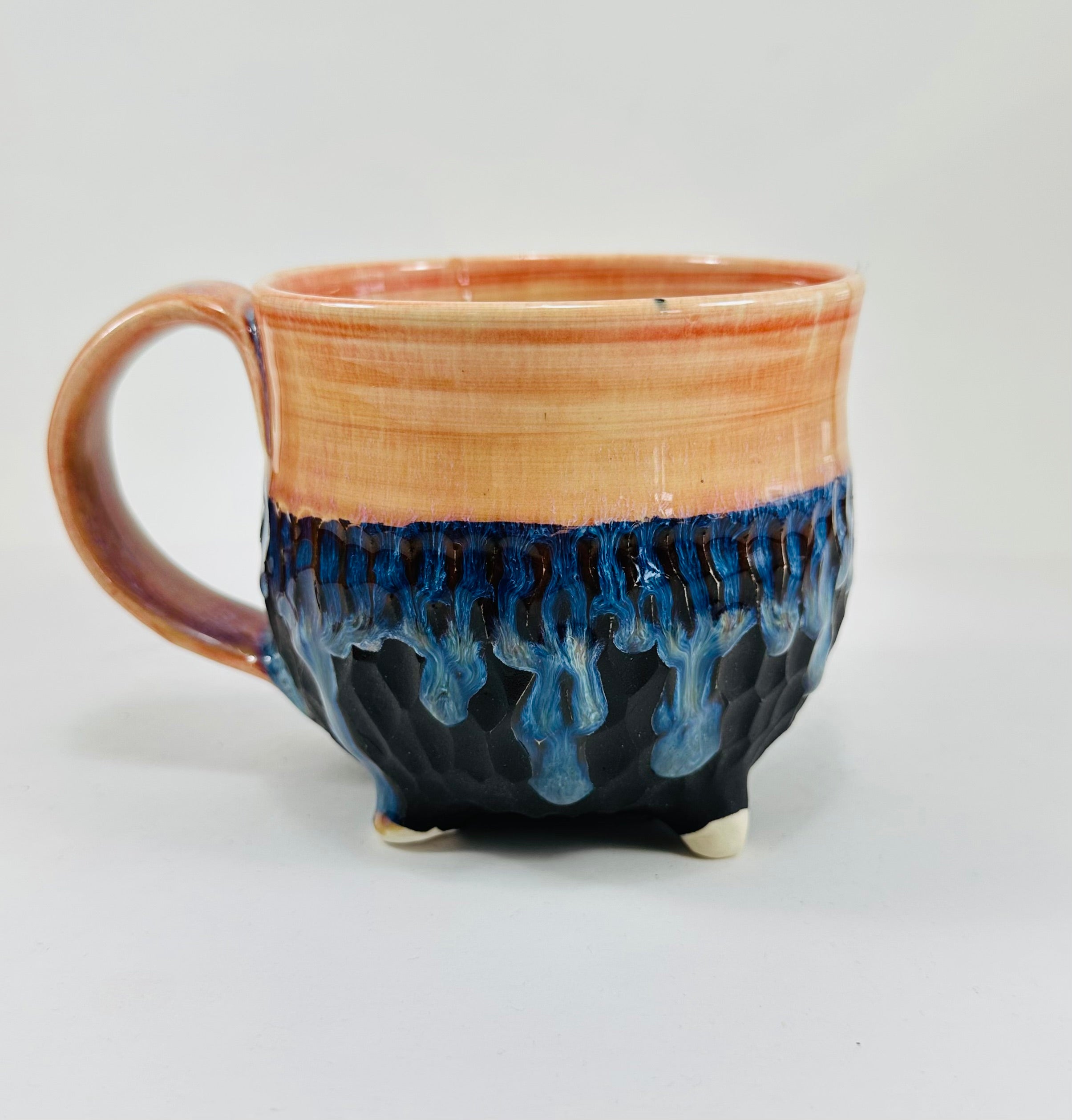 A handmade ceramic cauldron mug in a beautiful orange, blue  and black glaze