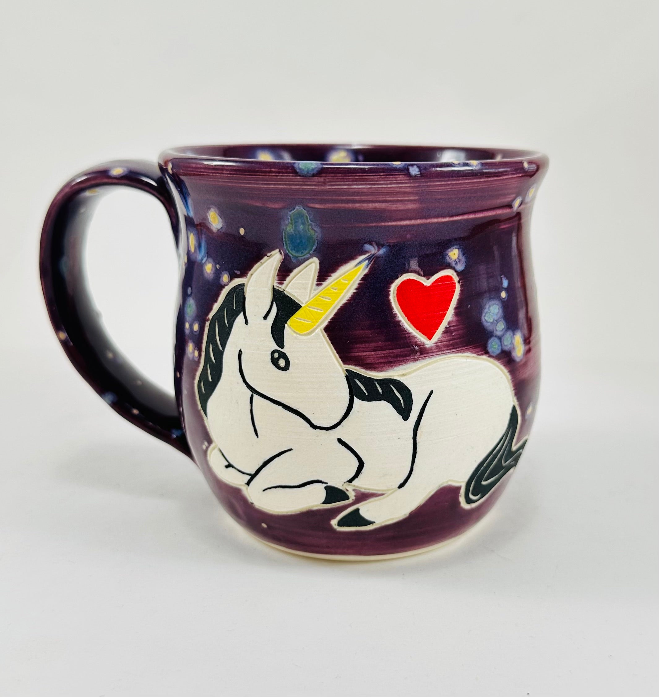 handmade ceramic mug in a beautiful purple glaze with a unicorn illustration on it