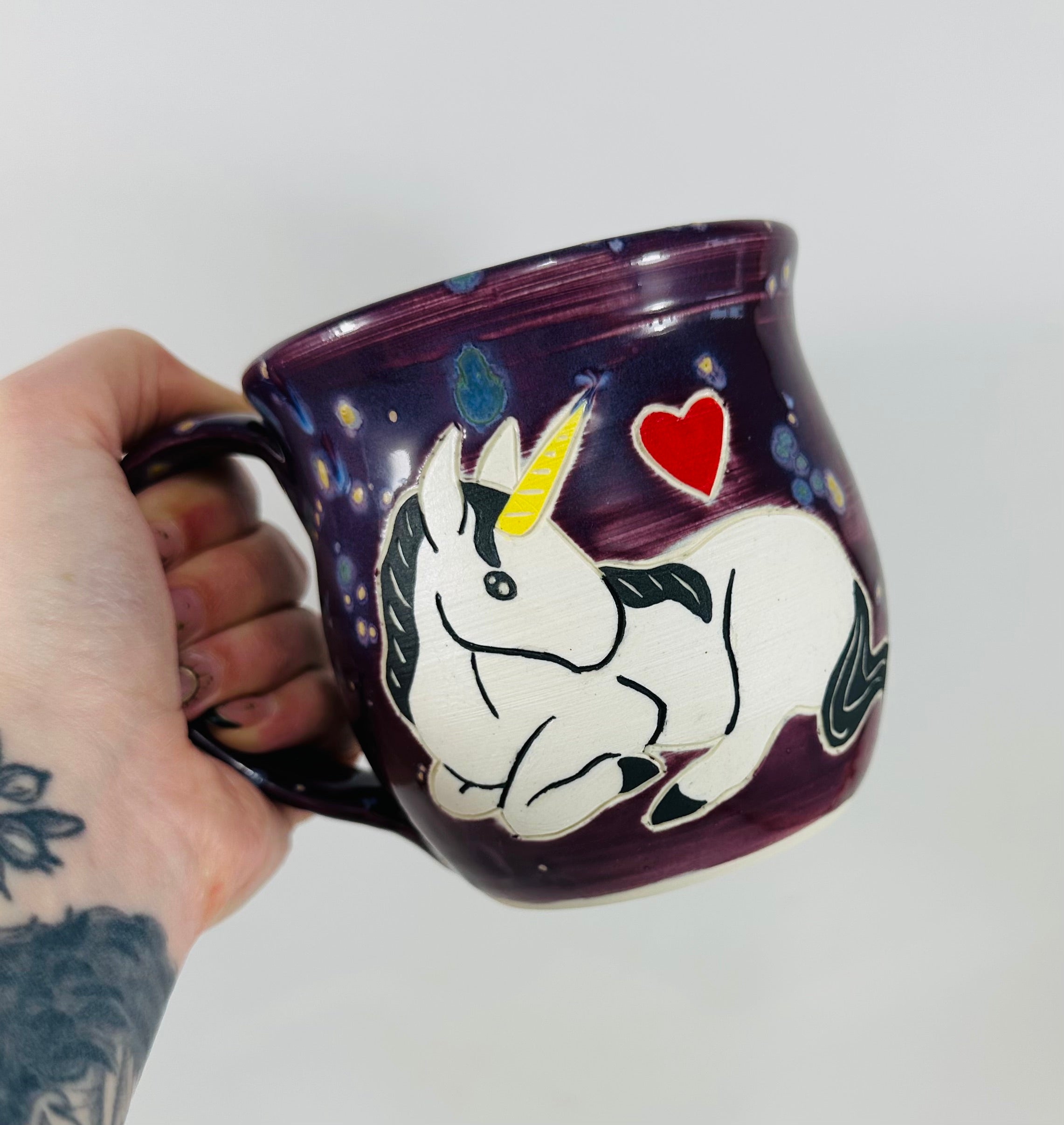 handmade ceramic mug in a beautiful purple glaze with a unicorn illustration on it